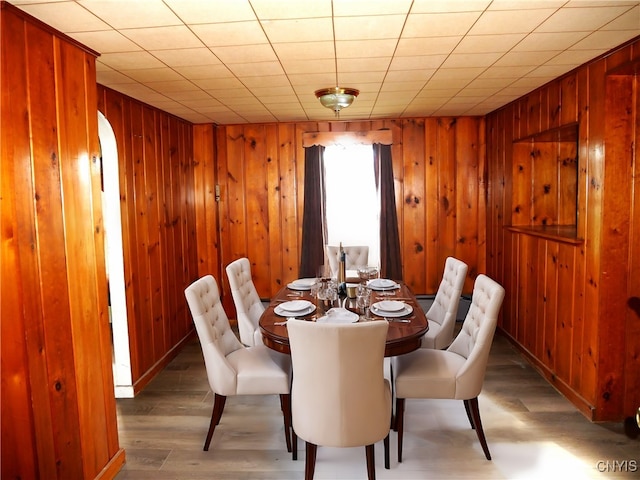 dining area with wooden walls and wood-type flooring