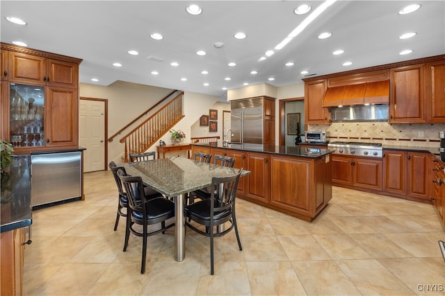 kitchen with a center island, premium range hood, backsplash, light tile patterned floors, and appliances with stainless steel finishes