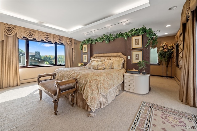 carpeted bedroom with a raised ceiling and a baseboard heating unit