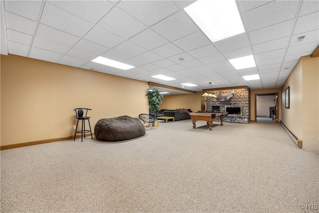 interior space with carpet flooring, a paneled ceiling, a baseboard radiator, and a brick fireplace