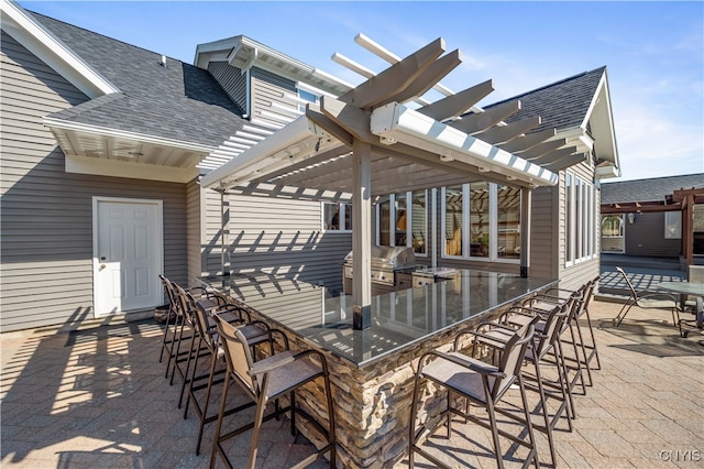 view of patio / terrace with a pergola, an outdoor bar, a grill, and exterior kitchen