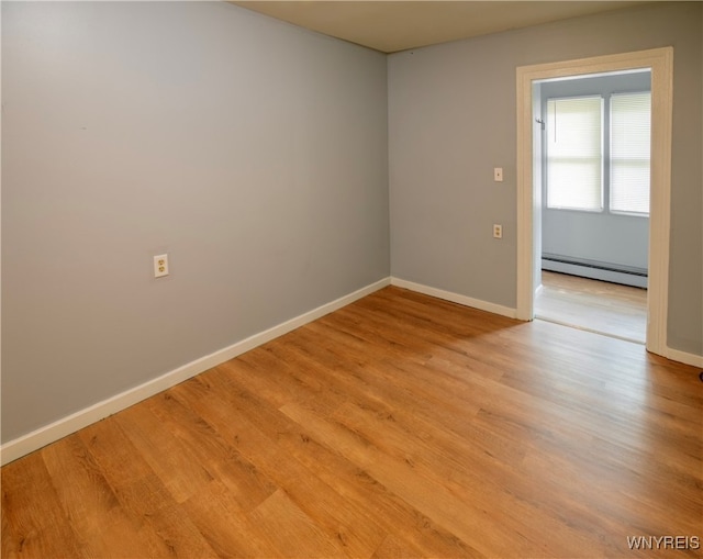 unfurnished room featuring a baseboard radiator and light hardwood / wood-style floors