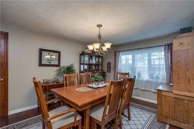 dining area featuring a textured ceiling, a notable chandelier, and hardwood / wood-style flooring