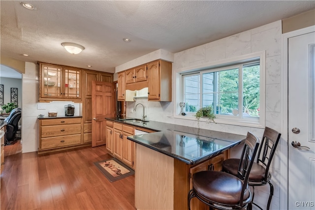 kitchen featuring sink, dark wood-type flooring, a kitchen breakfast bar, kitchen peninsula, and a textured ceiling