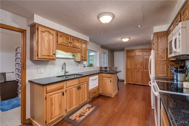 kitchen featuring a textured ceiling, light wood-type flooring, white appliances, and sink