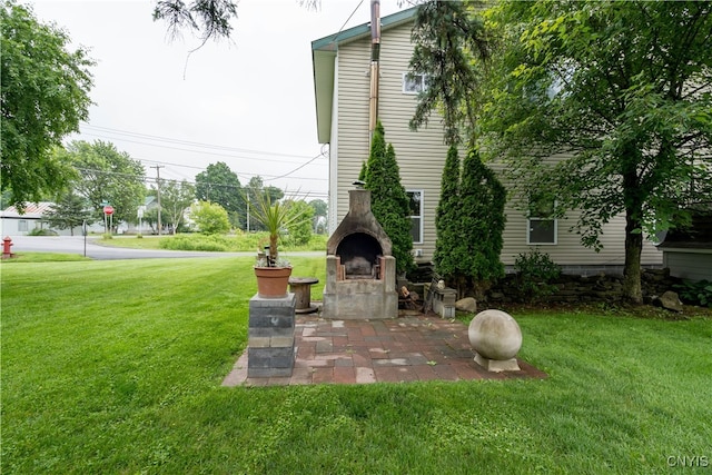 view of yard with an outdoor stone fireplace and a patio