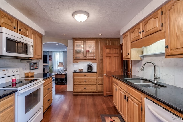 kitchen with tasteful backsplash, a textured ceiling, white appliances, dark wood-type flooring, and sink