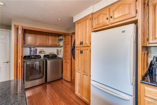 laundry room with washer and clothes dryer, light hardwood / wood-style floors, cabinets, and a textured ceiling