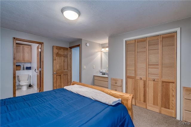 carpeted bedroom with a textured ceiling, ensuite bathroom, and a closet