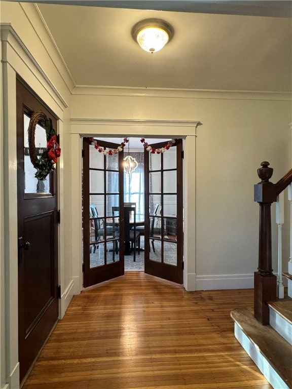 doorway with a chandelier, french doors, ornamental molding, and hardwood / wood-style flooring