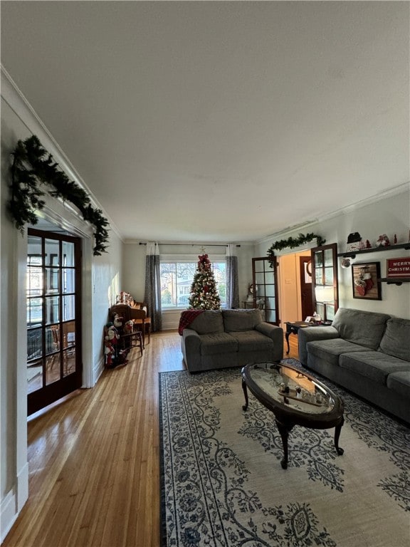 living room featuring ornamental molding, french doors, and light hardwood / wood-style flooring