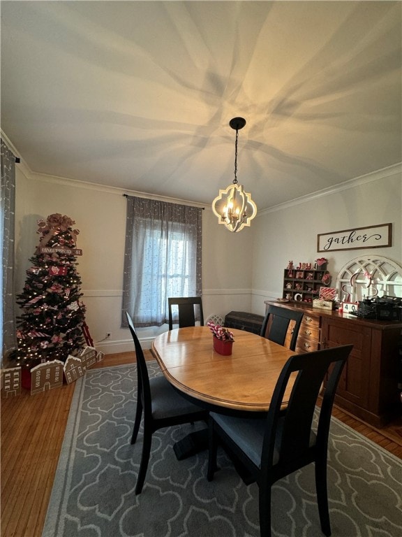 dining area featuring wood-type flooring, ornamental molding, and a chandelier