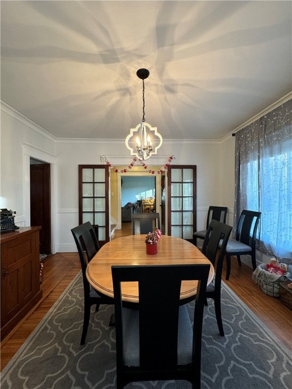 dining room with wood-type flooring, a notable chandelier, and ornamental molding