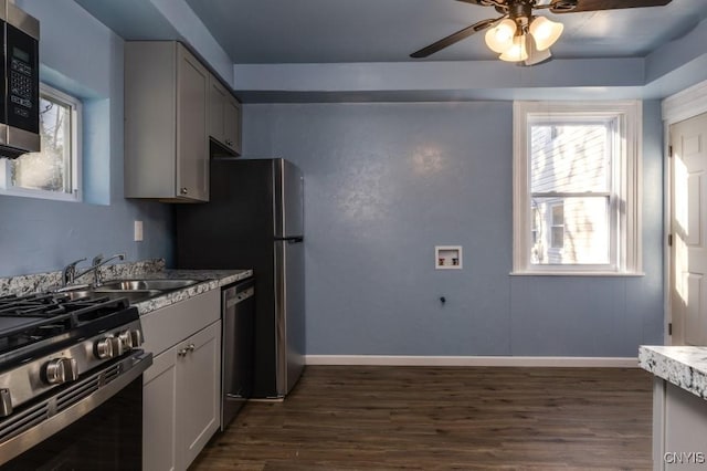 kitchen with appliances with stainless steel finishes, dark hardwood / wood-style flooring, ceiling fan, sink, and gray cabinets