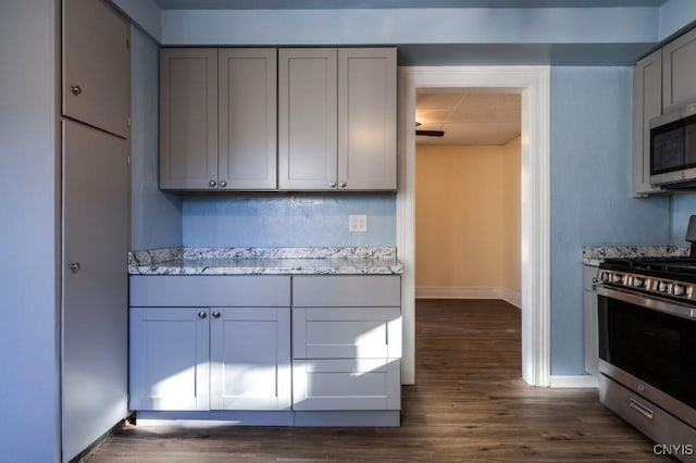 kitchen featuring dark hardwood / wood-style floors, gray cabinets, light stone countertops, and appliances with stainless steel finishes