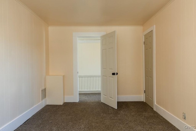 unfurnished bedroom featuring dark colored carpet, ornamental molding, and a closet