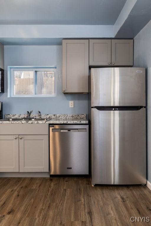 kitchen with light stone countertops, sink, dark hardwood / wood-style floors, and appliances with stainless steel finishes