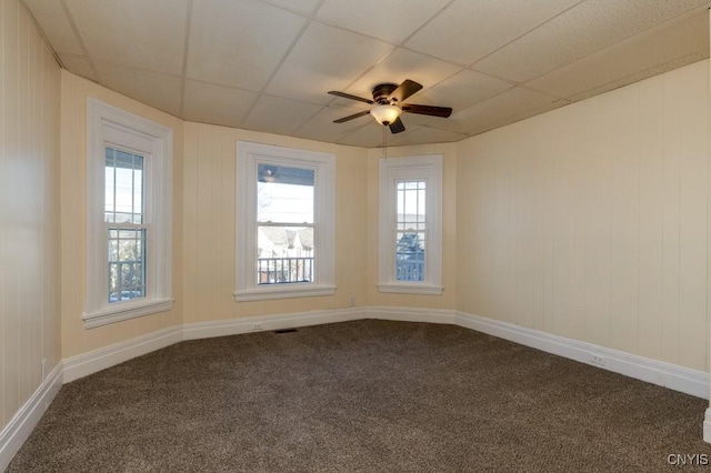 empty room with a paneled ceiling, ceiling fan, and carpet floors