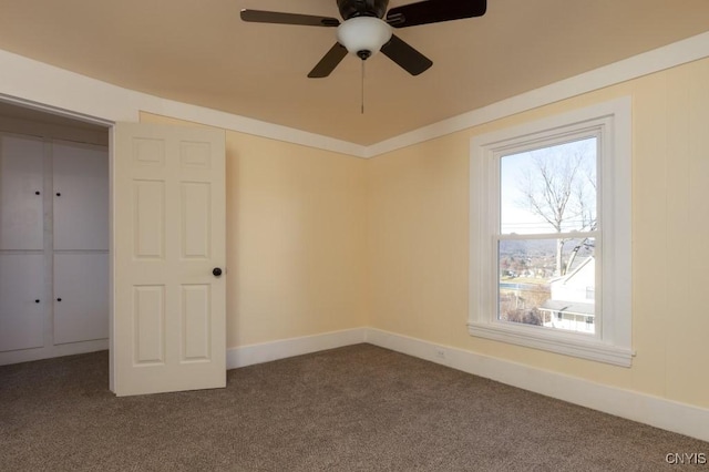 unfurnished bedroom featuring ceiling fan, a closet, and dark carpet