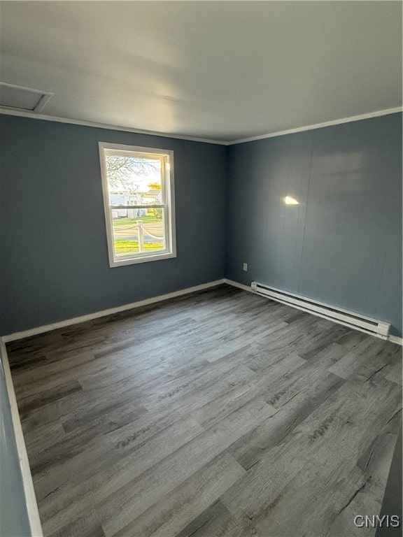 spare room with hardwood / wood-style flooring, baseboard heating, and crown molding