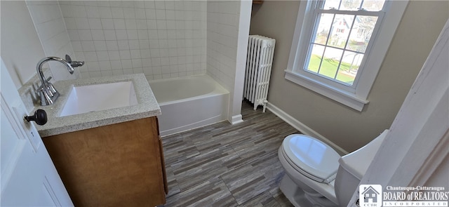 full bathroom with radiator, vanity, tiled shower / bath combo, wood-type flooring, and toilet