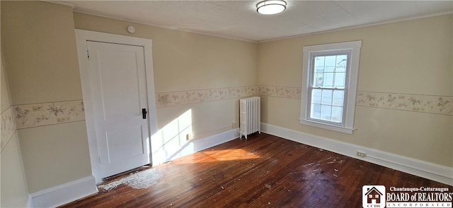 unfurnished room featuring dark hardwood / wood-style floors and radiator heating unit