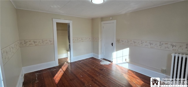 spare room featuring crown molding, dark wood-type flooring, and radiator