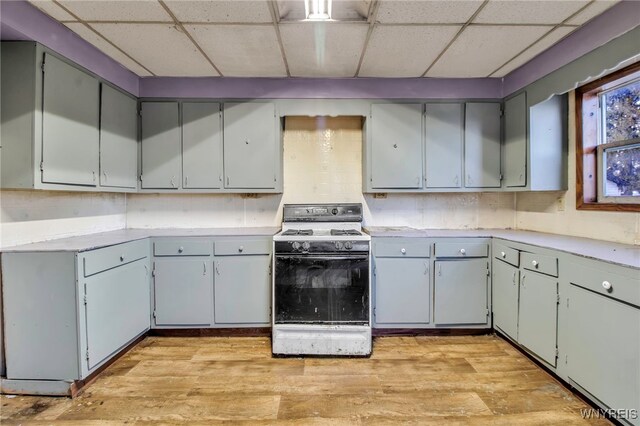 kitchen with decorative backsplash, white range, light hardwood / wood-style floors, and a drop ceiling