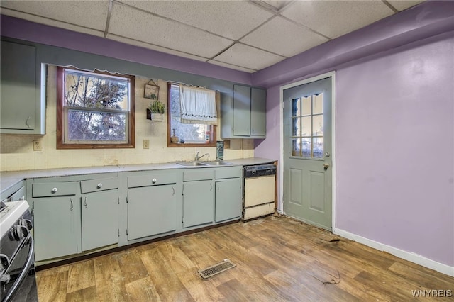 kitchen featuring sink, a drop ceiling, stove, white dishwasher, and light wood-type flooring