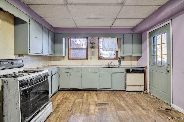 kitchen featuring light wood-type flooring, white appliances, plenty of natural light, and a paneled ceiling