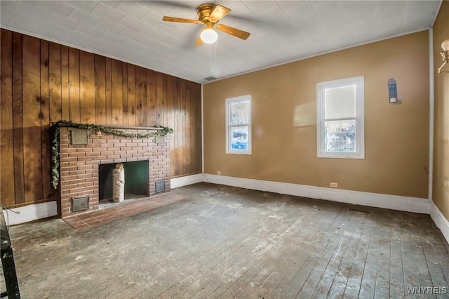 unfurnished living room with hardwood / wood-style floors, a brick fireplace, ceiling fan, and wooden walls