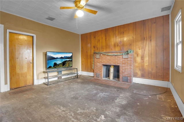 unfurnished living room featuring a healthy amount of sunlight, a fireplace, and wooden walls