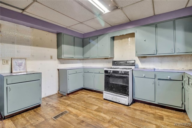 kitchen with a paneled ceiling, white range with gas stovetop, and light hardwood / wood-style flooring