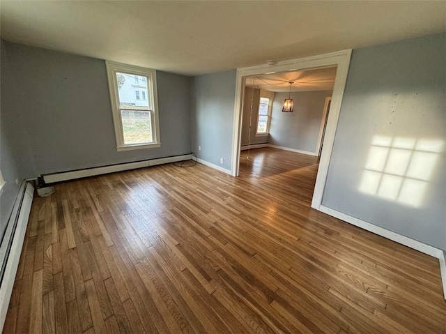 unfurnished room featuring wood-type flooring, a baseboard radiator, and a notable chandelier