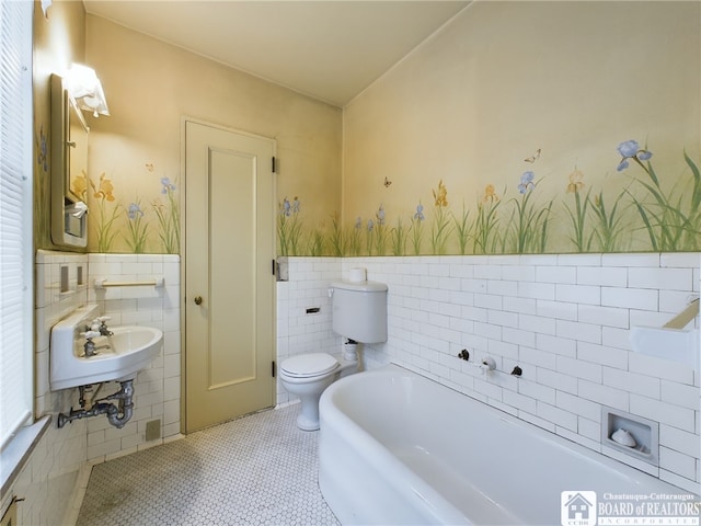 bathroom featuring a washtub, tile patterned floors, toilet, and tile walls