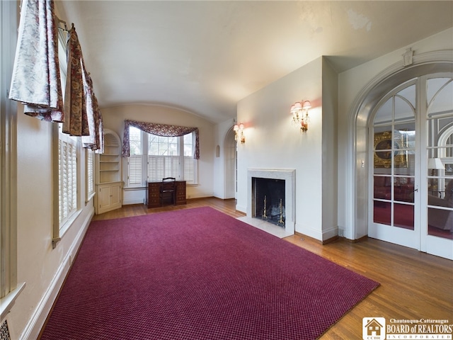 unfurnished living room featuring lofted ceiling, wood-type flooring, and french doors