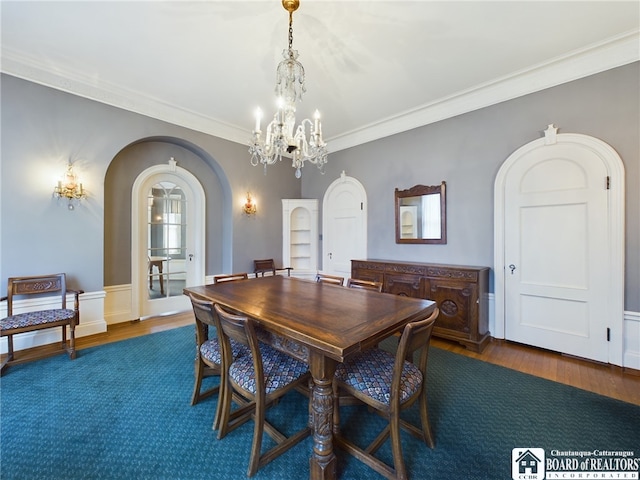 dining space with crown molding, dark wood-type flooring, and an inviting chandelier