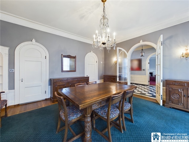 dining area with crown molding, dark wood-type flooring, and an inviting chandelier