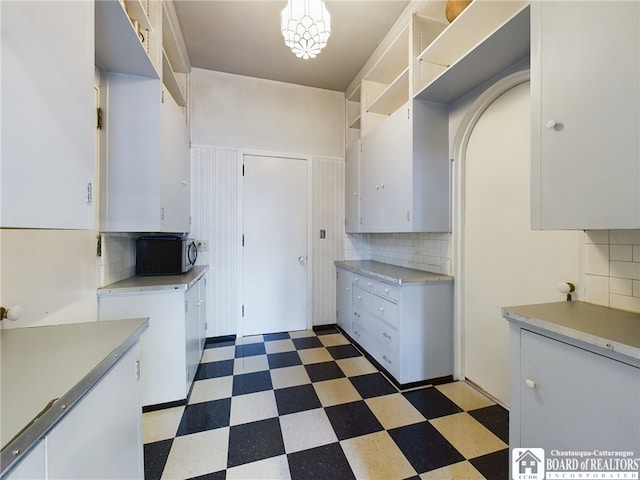 kitchen featuring backsplash, decorative light fixtures, and white cabinetry