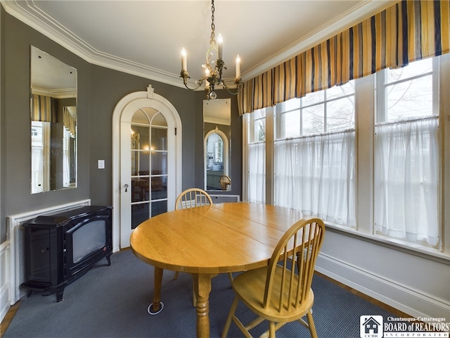 dining space featuring a wood stove, crown molding, and a notable chandelier