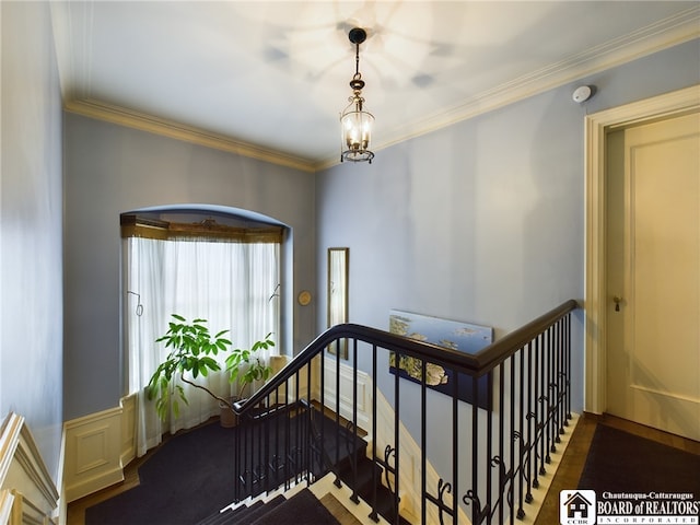 stairway with a chandelier, hardwood / wood-style flooring, and crown molding