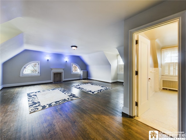 additional living space featuring lofted ceiling, radiator heating unit, and dark hardwood / wood-style floors