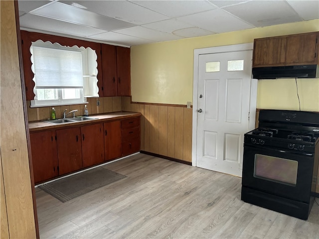 kitchen with a drop ceiling, black range with gas cooktop, ventilation hood, sink, and light hardwood / wood-style flooring