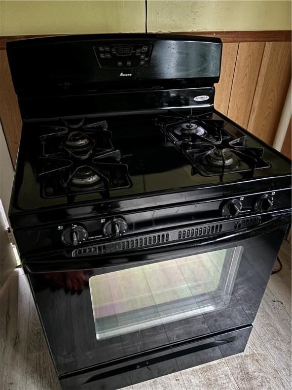 details with wood-type flooring and black range with gas cooktop