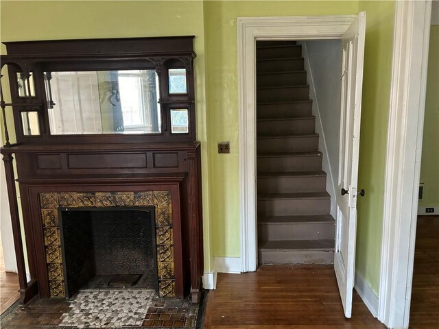 stairway with a tiled fireplace and hardwood / wood-style flooring