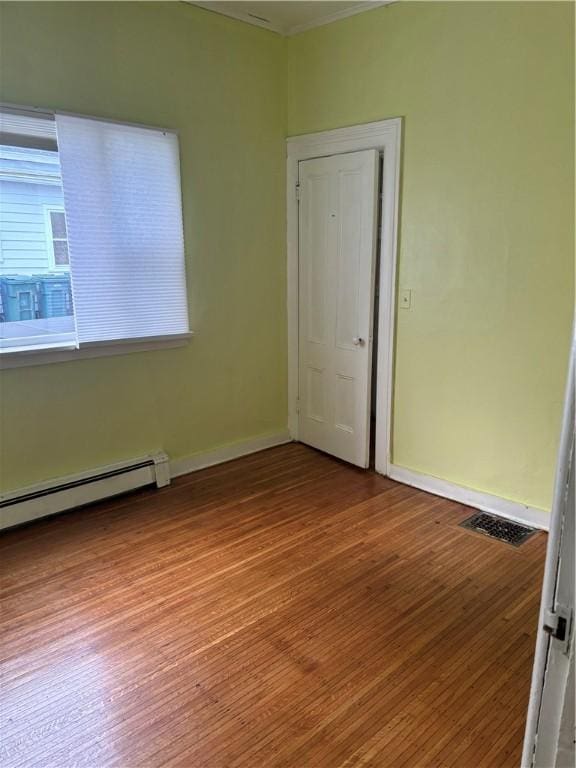 empty room with hardwood / wood-style flooring and a baseboard radiator