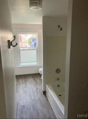 bathroom featuring toilet, wood-type flooring, and bathtub / shower combination