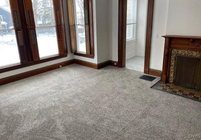 unfurnished living room featuring visible vents, baseboards, and carpet flooring