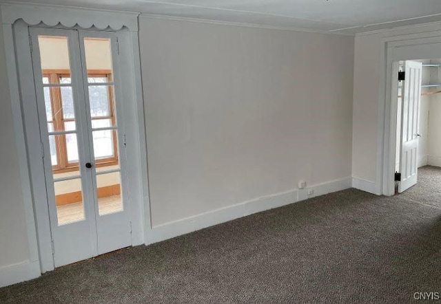 empty room featuring dark carpet, crown molding, baseboards, and french doors