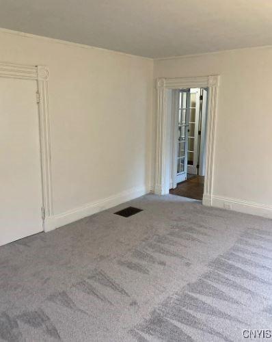 unfurnished room featuring visible vents, carpet flooring, and baseboards